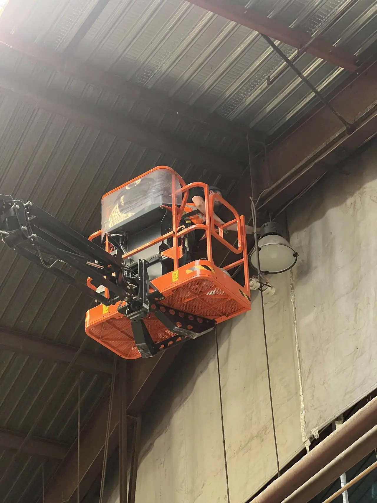 Technicien en nacelle pendant le remplacement d’un luminaire industriel sur le site Siplast Loriol